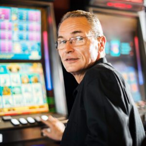 A man sitting in front of a slot machine.