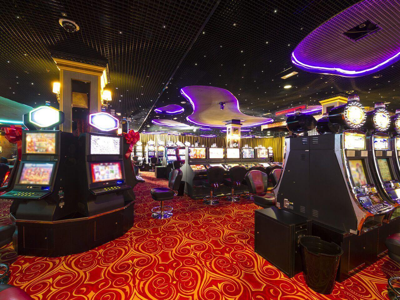 A room with several slot machines and a red carpet.