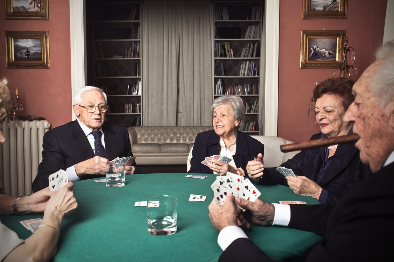 A group of people sitting around a table playing cards.