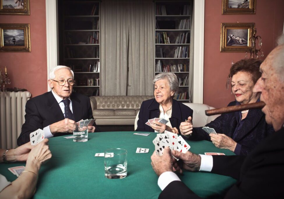 A group of people sitting around a table playing cards.
